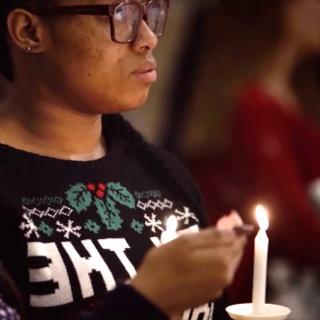 Illuminated by handheld candles, two female TCU students listen to a Christmas service in the TCU Chapel.